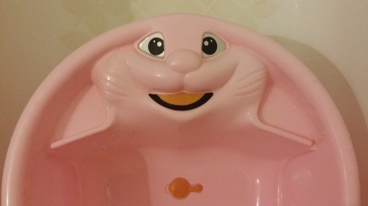 Pink baby bath with a large rabbit's face on it. 